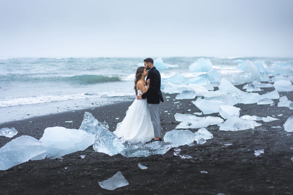 Wedding couple on Diamond Beach in Iceland surrounded by glacial ice on black sand